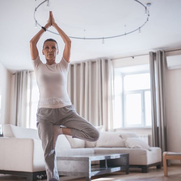 A person doing a gentle stretching exercise on a yoga mat in a bright room.